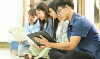 A team of young people sitting on the floor using laptops and tablets. photo