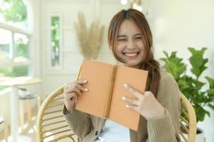 Beautiful girl holding a book and smiling at the camera. photo