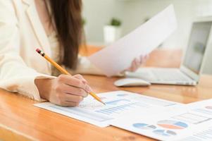 Close-up shot of A businesswoman holding a pencil checking data on a graph in the office photo