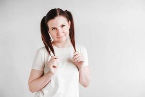 Woman with pigtails and a funny face wearing a T-shirt on a white background. Copy, empty space photo