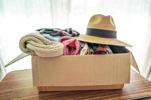 sosteniendo una caja de donación de ropa con ropa usada y sombrero en casa para ayudar a los pobres del mundo.