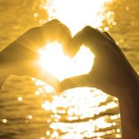 corazón en forma de mano contra la puesta de sol. concepto del día de san valentín foto
