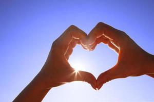 corazón en forma de mano contra la puesta de sol. concepto del día de san valentín foto
