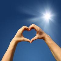 corazón en forma de mano contra la puesta de sol. concepto del día de san valentín foto