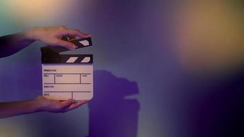 Hand holds empty film making clapperboard on color background in studio photo