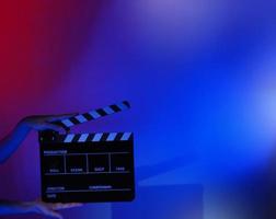 Hand holds empty film making clapperboard on color background in studio photo