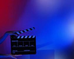 Hand holds empty film making clapperboard on color background in studio photo