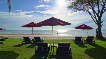 rött paraply och strandstol med havsstrandbakgrund och blå himmel och solljus video