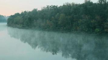 fumo sull'acqua. la nebbia galleggia sul fiume al mattino presto all'alba. un bellissimo lago sullo sfondo del verde bosco. superficie dell'acqua. affascinanti miracoli della natura. copia spazio per il testo video