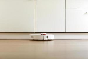 Robot vacuum cleaner performs automatic cleaning of the apartment at a certain time. white robot vacuum cleaner. home cleaning. Smart home. selective focus photo