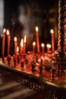 long lighted candles group in orthodox church. candles background. selective focus photo