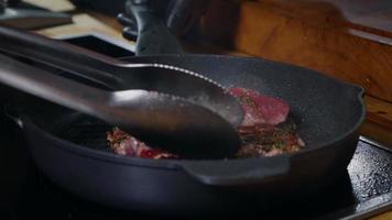 apetitoso bistec de ternera cocinado en una sartén sazonado con hierbas. video