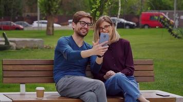 Happy couple wearing eye glasses waving hands at camera during video chat.