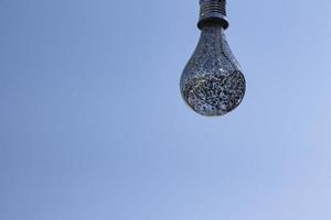 A light bulb against a blue sky. Close up the light bulb. Blue sky background. Decorative light bulb. photo