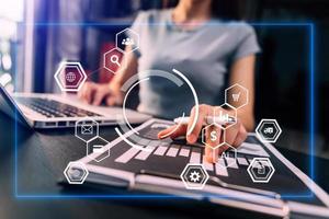 Hands of woman using mobile phone in modern office with laptop and digital tablet computer with VR icon diagram at office in morning light photo