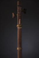 antiguo instrumento musical de cuerda asiático sobre fondo negro con retroiluminación. clavija de afinación foto