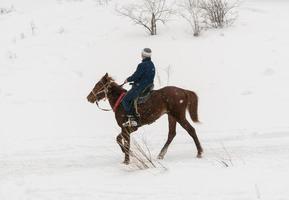 hombre a caballo en las montañas de invierno foto