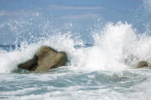 alta ola rompiendo en las rocas de la costa. foto