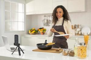 Latin woman shooting video and cooking at the kitchen photo