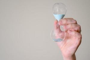 Hourglass in the hands of a man on a light background. photo
