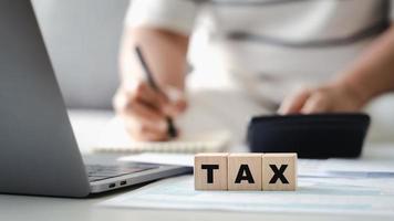 Woman is calculating annual tax with calculator and filling form of Individual Income Tax Return. Season to pay Tax and Budget planning concept. photo