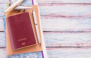 Flat lay photo with notebook, pen,map,passport and airplane on wooden table background.