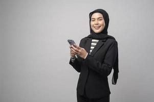 retrato de una mujer hermosa con hiyab usando un teléfono celular con fondo blanco foto