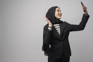 Portrait of beautiful woman with hijab using cellphone on white background photo