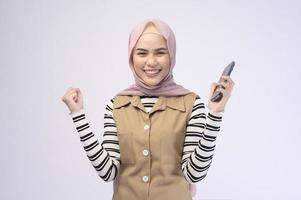 Portrait of beautiful woman with hijab using cellphone on white background photo