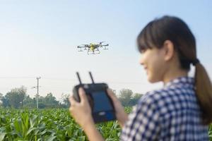 Young smart farmer controlling drone spraying fertilizer and pesticide over farmland,High technology innovations and smart farming photo