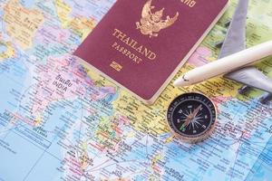 cierre el avión de juguete blanco y el pasaporte en el fondo del mapa mundial. foto