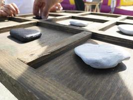 juego de tres en raya hecho con madera y piedras foto