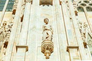 Facade of Milan Cathedral Duomo di Milano with Gothic spires and white marble statues. Top tourist attraction on piazza in Milan, Lombardia, Italy. Wide angle view of old Gothic architecture and art. photo