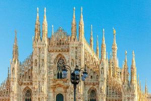 Famous church Milan Cathedral Duomo di Milano with Gothic spires and white marble statues. Top tourist attraction on piazza in Milan Lombardia Italy. Wide angle view of old Gothic architecture and art photo