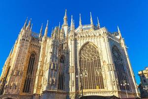 Famous church Milan Cathedral Duomo di Milano with Gothic spires and white marble statues. Top tourist attraction on piazza in Milan Lombardia Italy. Wide angle view of old Gothic architecture and art photo