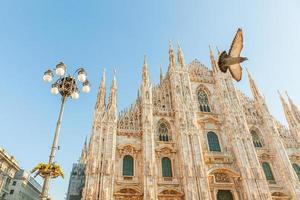 Famous church Milan Cathedral Duomo di Milano with Gothic spires and white marble statues. Top tourist attraction on piazza in Milan Lombardia Italy. Wide angle view of old Gothic architecture and art photo