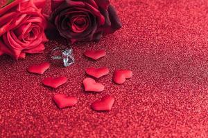 Will you marry me. Wedding ring red scarlet roses and many red hearts on red glitter background. Engagement marriage proposal wedding concept. St. Valentine's Day postcard. Banner on valentines day. photo