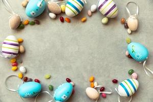 Happy Easter concept. Preparation for holiday. Easter eggs candy chocolate eggs and jellybean sweets on concrete stone grey background. Flat lay top view copy space banner. photo