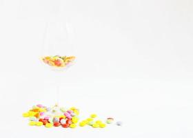 colorful chocolate coated candy sweet food into wine glass on white backgrounds photo