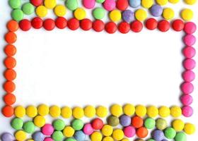 Frame with a pile of colorful chocolate coated candy on white backgrounds photo