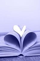 un libro abierto con un corazón de madera sobre la mesa. concepto amor por la lectura, libros. biblioteca, educación. espacio de copia de primer plano foto