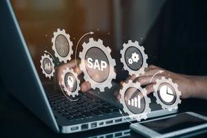 Person working on computer with icons of SAP - Business process automation software. ERP enterprise resources planning system concept on virtual screen. photo