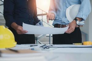 Builder two asian young engineer man construction site engineer. Engineering objects on workplace with partners interacting on background. Real-estate concept photo