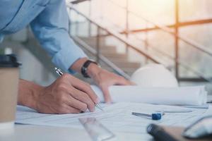 Business man construction site engineer. Engineering objects on workplace with partners interacting on background. architectural plan,sketching a construction project ,selective focus,Business concept photo