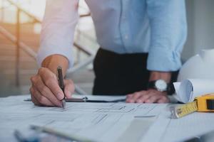 Business man construction site engineer. Engineering objects on workplace with partners interacting on background. architectural plan,sketching a construction project ,selective focus,Business concept photo