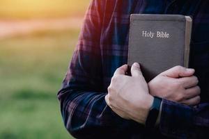 Man in hold and hugging holy bible on the bench. christian praying believe concept. photo