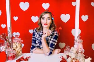 Beautiful young woman in pin-up style on red with white hearts background photo