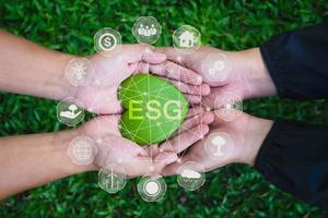 Adult hands holding green heart with ESG icon concept for environmental, social, and governance in sustainable and ethical business on the Network connection on a green background. photo