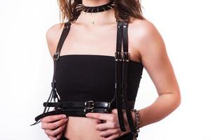 Leather, elegant, black swordbelt in the torso of young female model over the black top on white background. isolate photo