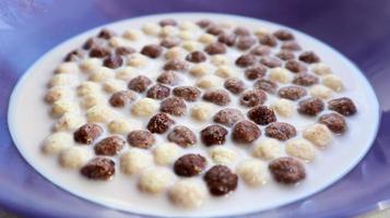 Healthy breakfast with milk on the table in a deep plate. Whole grain chocolate and milk balls. Healthy cereal breakfast. Children's breakfast. Baby food. Balanced diet. Dry ready and quick snack photo